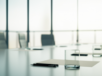 Board meeting room, showing the desk up close with paper and a glass.